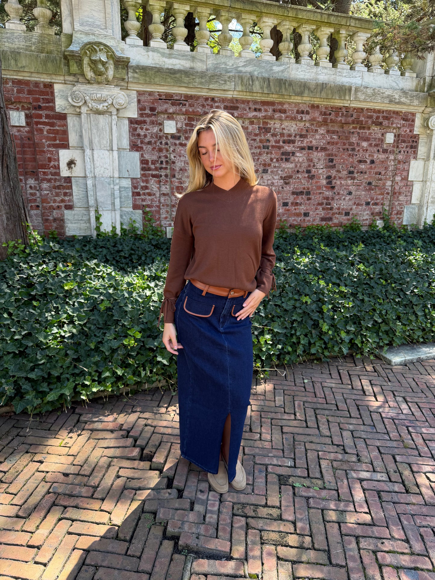 Another view of blue denim maxi skirt with chestnut leather trim detail, front flap pockets and zipper closure slit