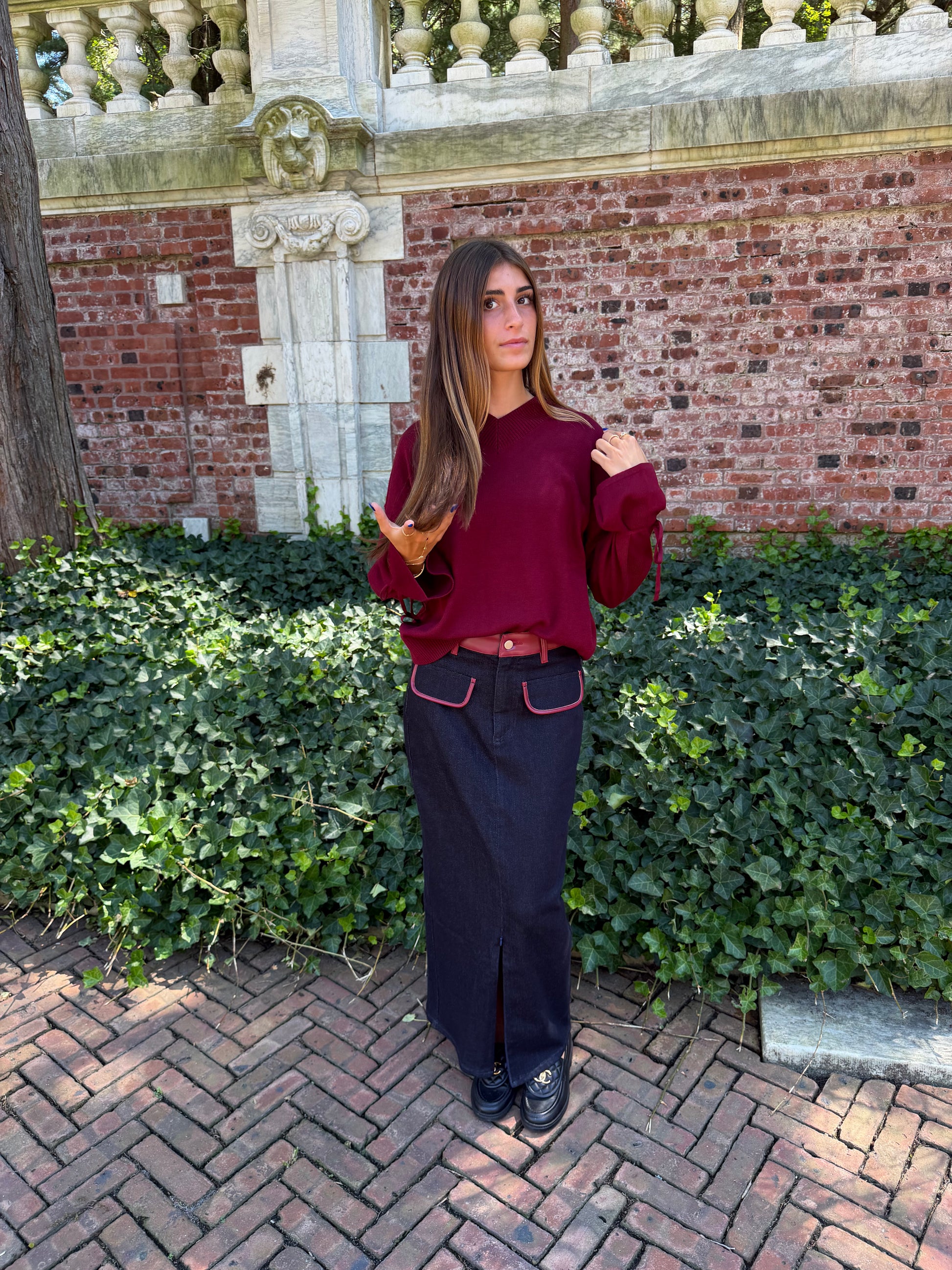 Another front view of black denim maxi skirt with burgundy leather trim detail, front flap pockets and zipper closure slit