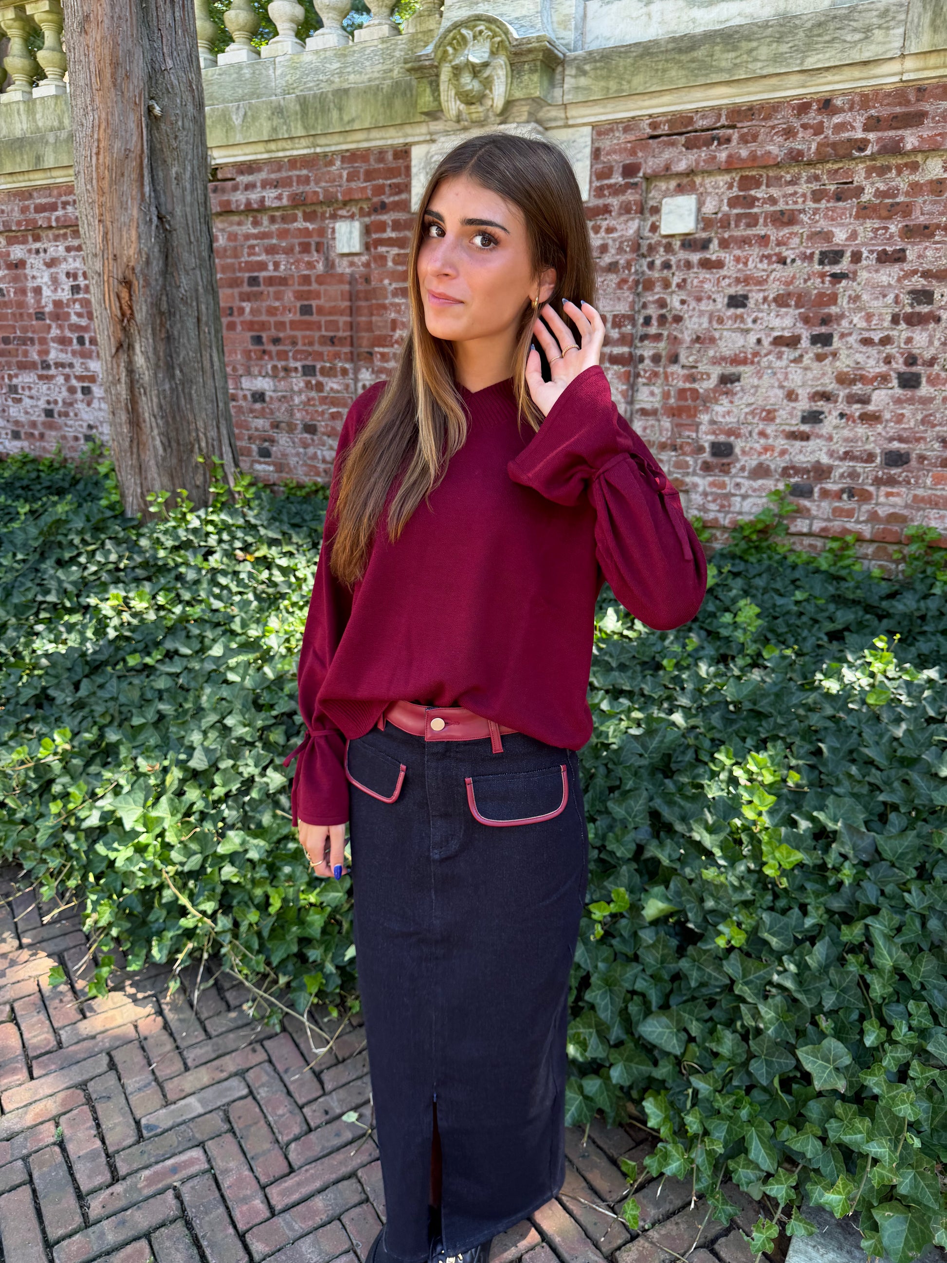 Second front view of burgundy v-neck sweater with tie sleeve detail