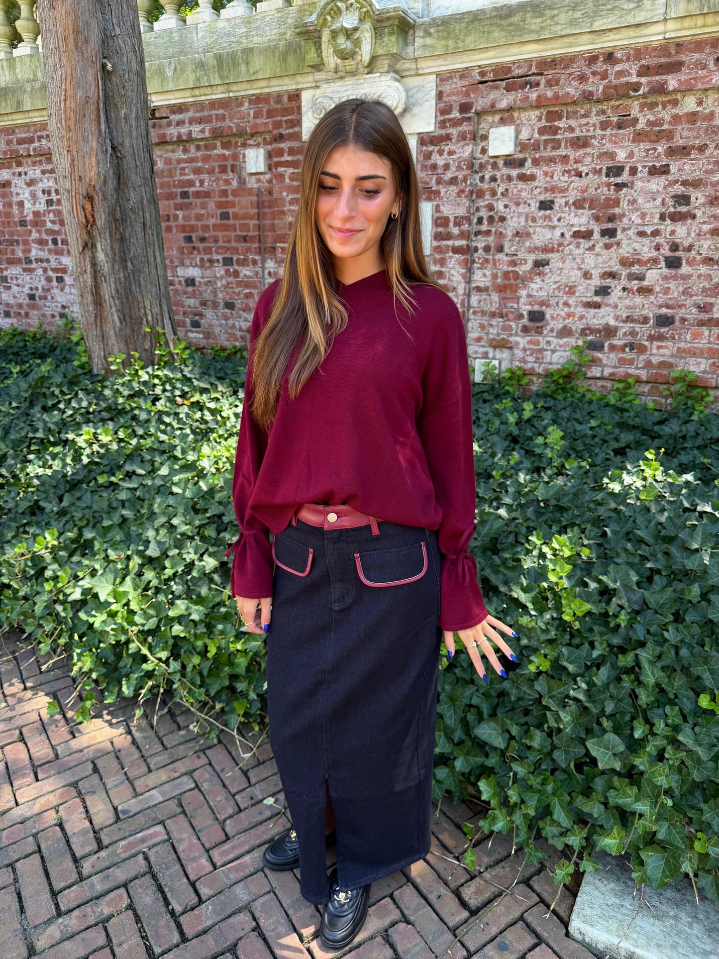 Third front view of burgundy v-neck sweater with tie sleeve detail