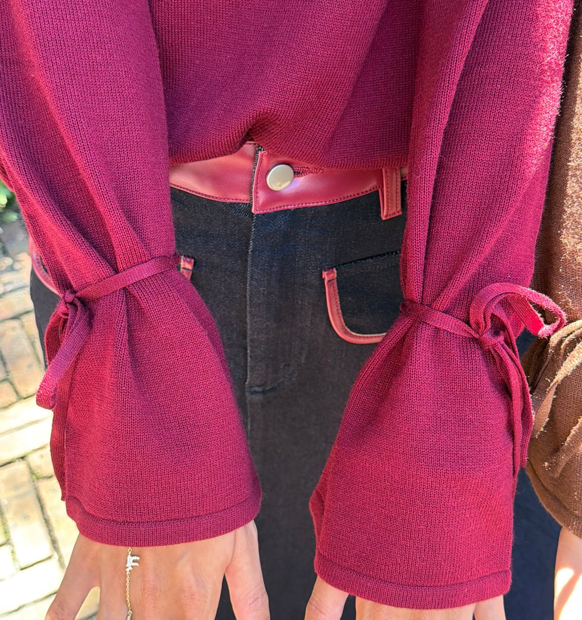 Close up view of burgundy v-neck sweater tie sleeve detail