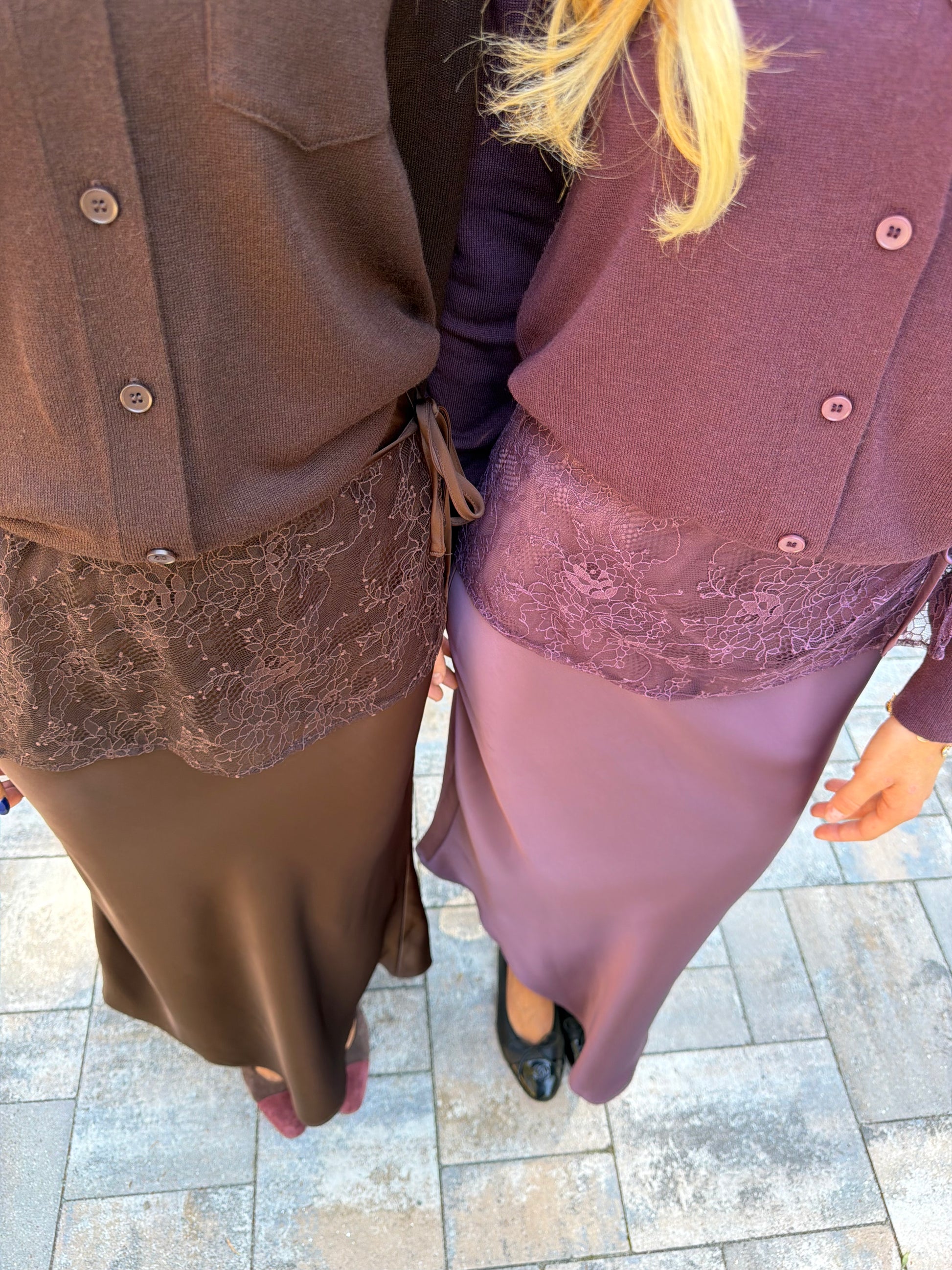Close up view of chocolate brown and plum slip skirt with lace overlay and coordinating cardigan tucked in
