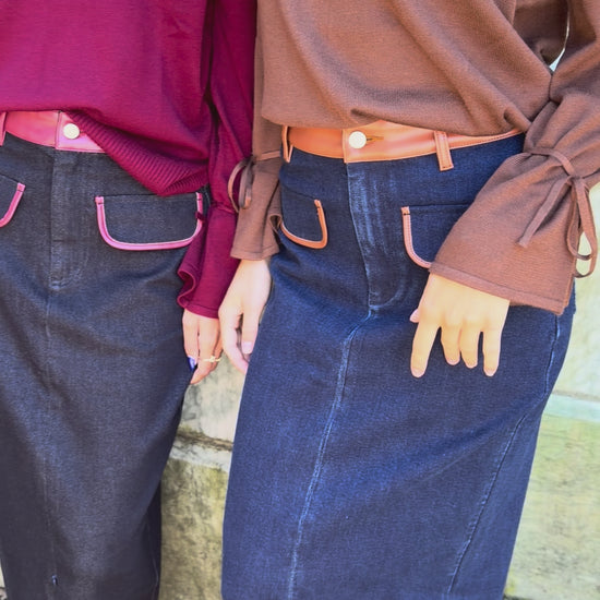 Video of blue denim maxi skirt with chestnut leather trim detail, front flap pockets and zipper closure slit and black denim maxi skirt with burgundy leather trim detail, front flap pockets and zipper closure slit